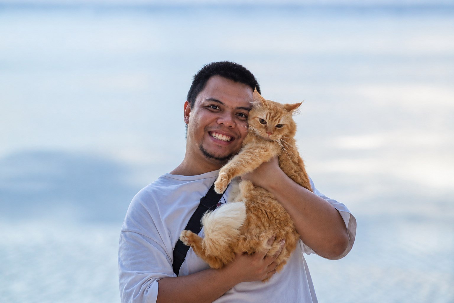 Christian Loterte, Business Operations Assistant, holding his ginger cat